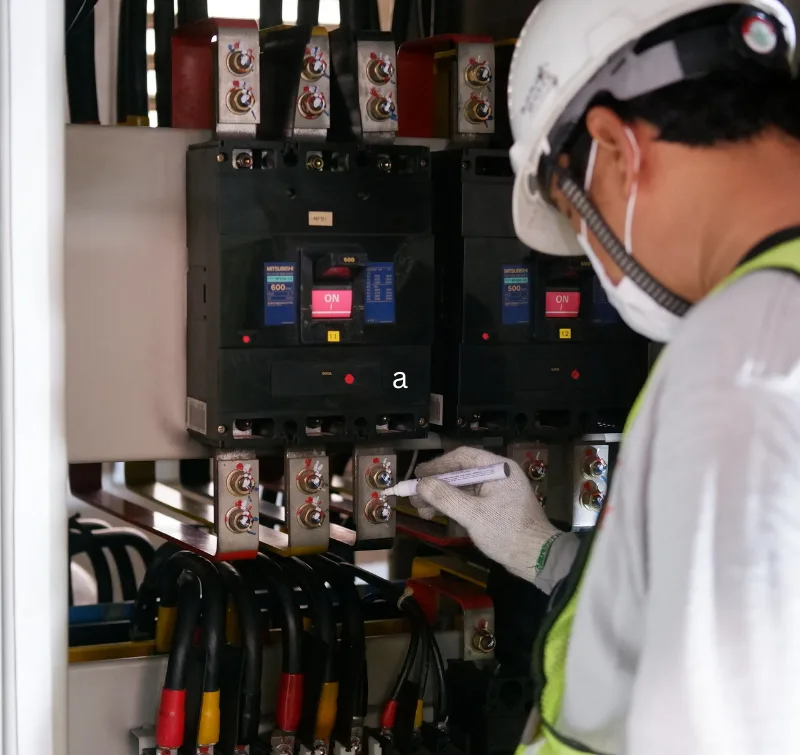 Technician in PPE inspecting power distribution breakers in a critical facility